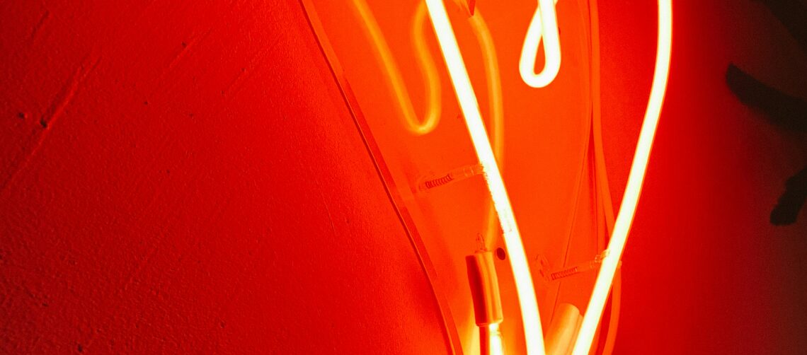 Photo of a red, glowing, neon heart against a wall. Photo by Alina Rubo on Unsplash