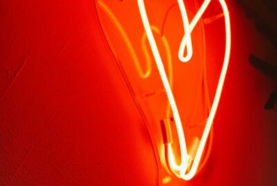 Photo of a red, glowing, neon heart against a wall. Photo by Alina Rubo on Unsplash