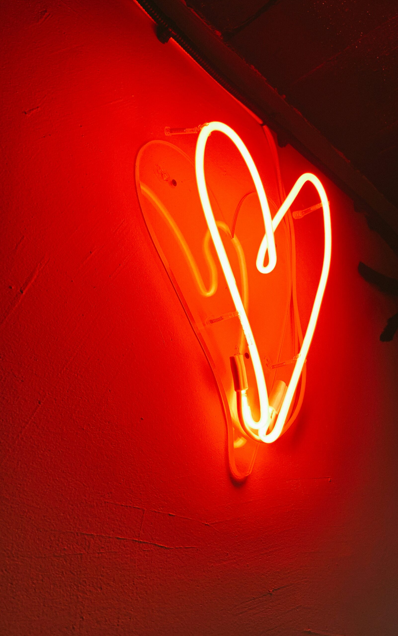 Photo of a red, glowing, neon heart against a wall. Photo by Alina Rubo on Unsplash