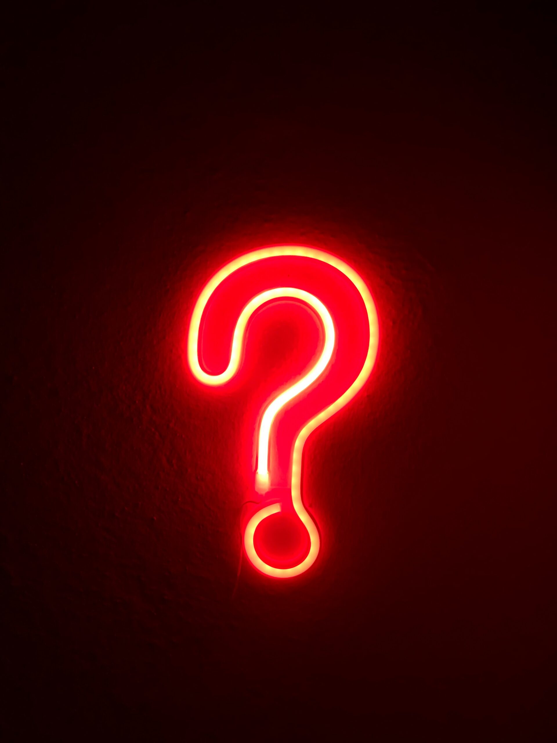 Photo of a red, neon question mark against a black wall. Photo of a red, glowing, neon heart against a wall. Photo by Alina Rubo on Unsplash