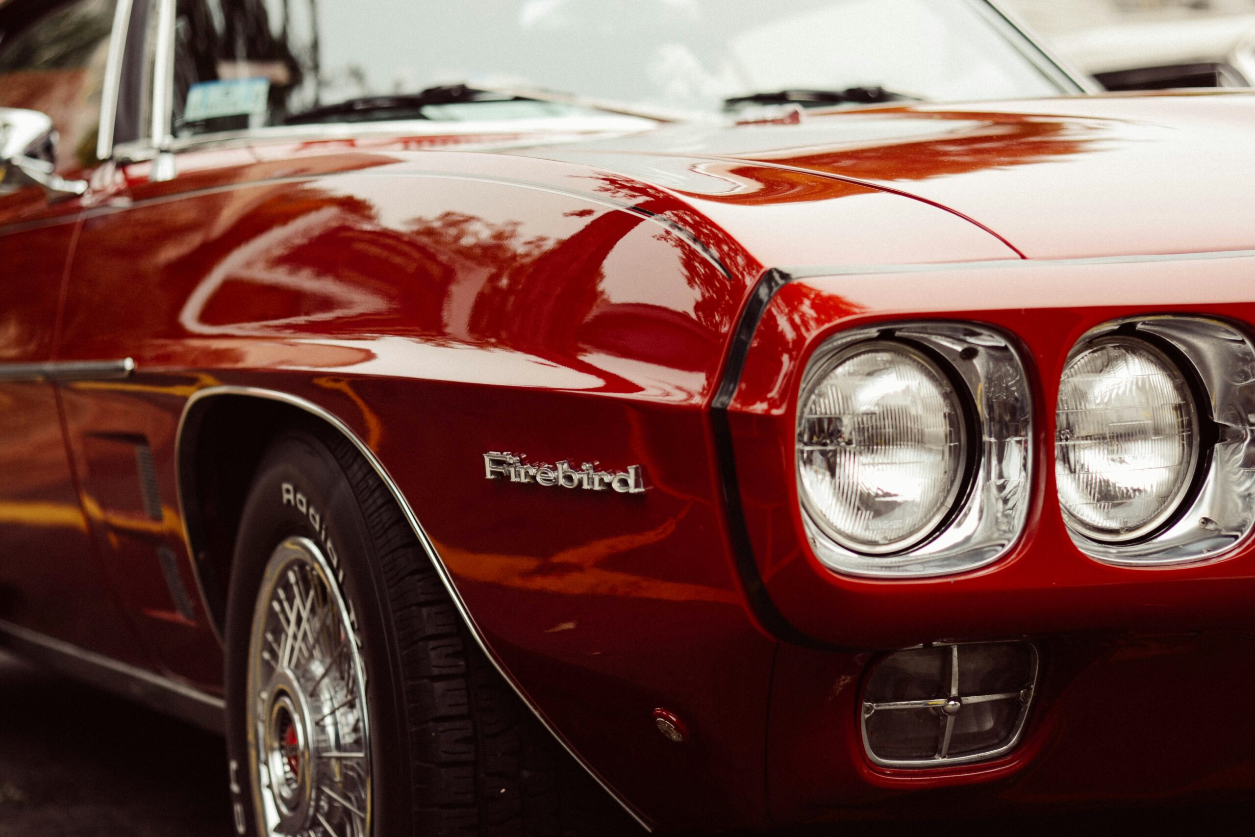 Photo of a dark red old Firebird car with black pinstripes. Photo by David Straight on Unsplash
